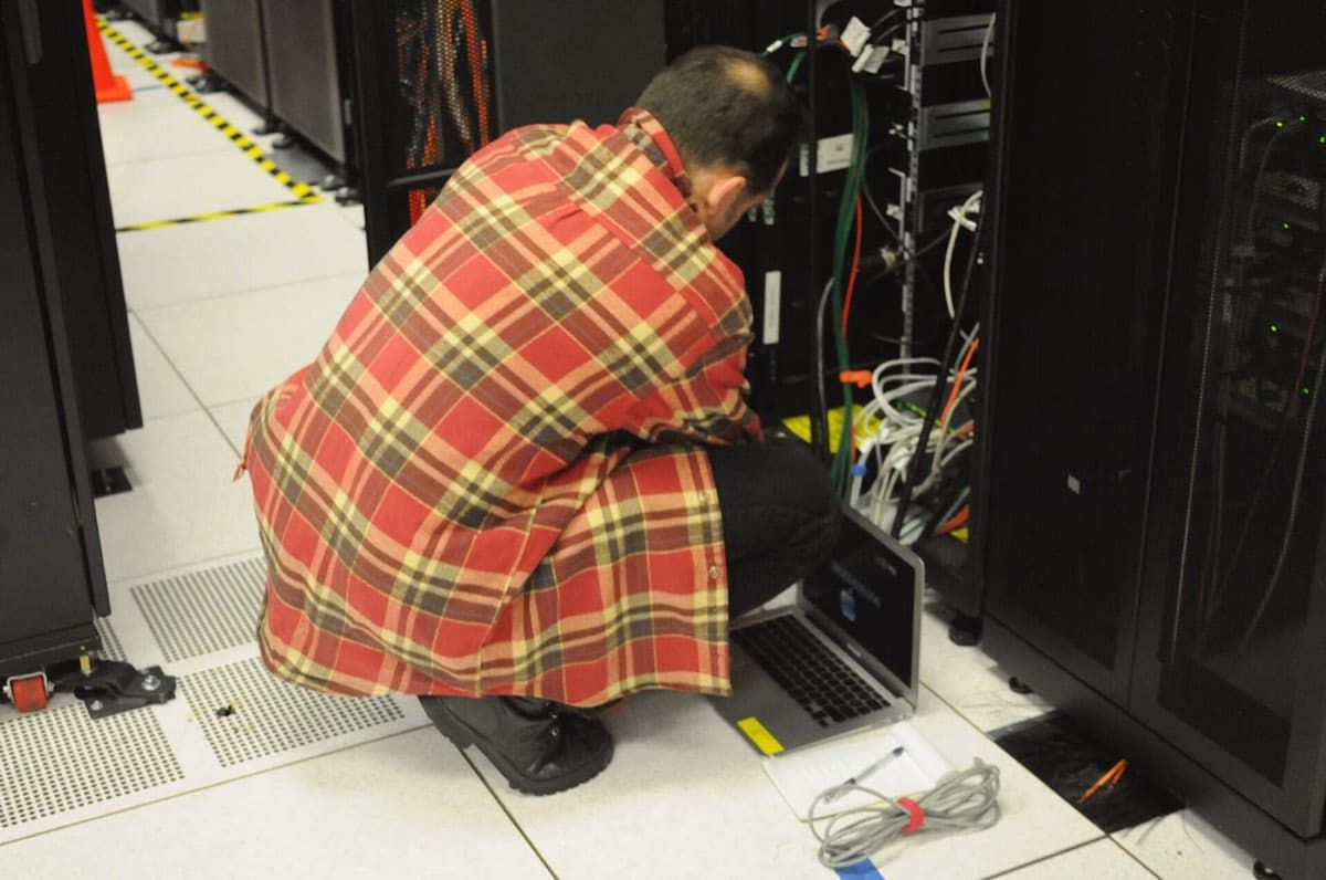 Technician working on a server rack inside a supercomputing data center, illustrating how AI data centers work