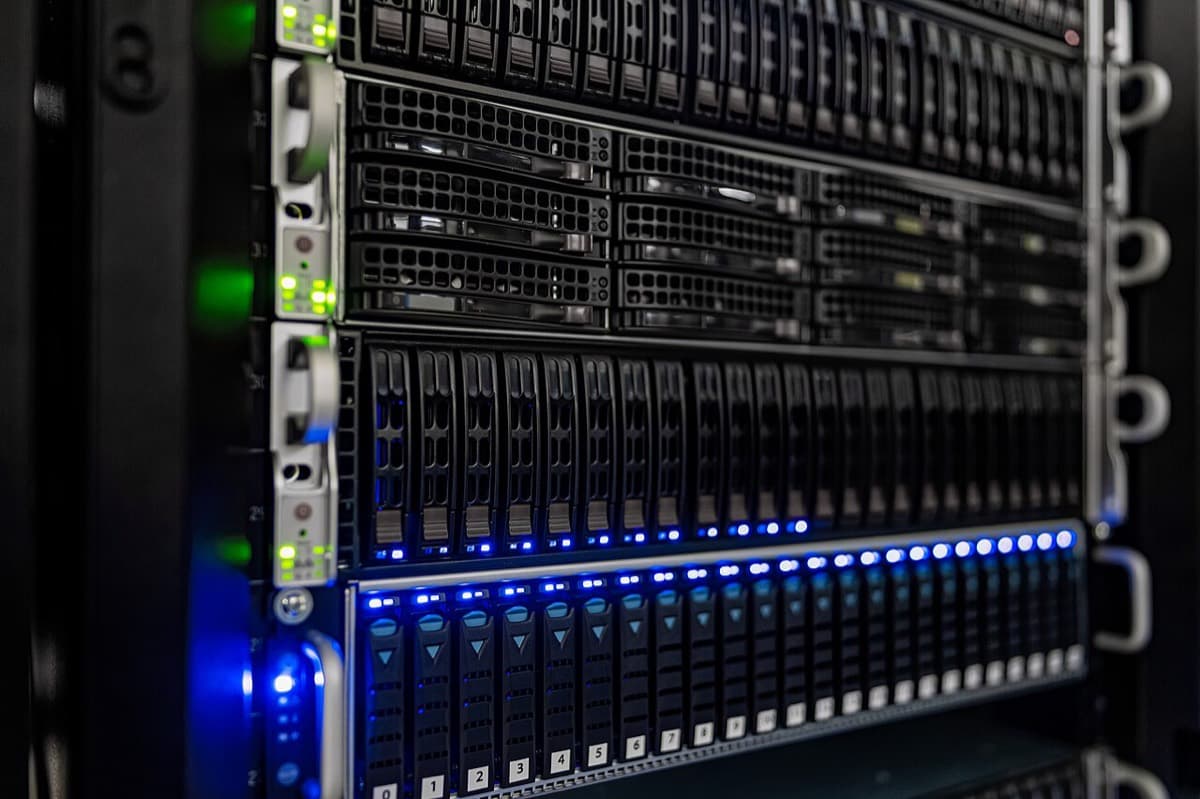 Close-up of a data center server rack with blue and green status lights, the kind of hardware that runs AI inference for every chat answer (photo CC BY 4.0, NOIRLab/NSF/AURA/T. Slovinsky)