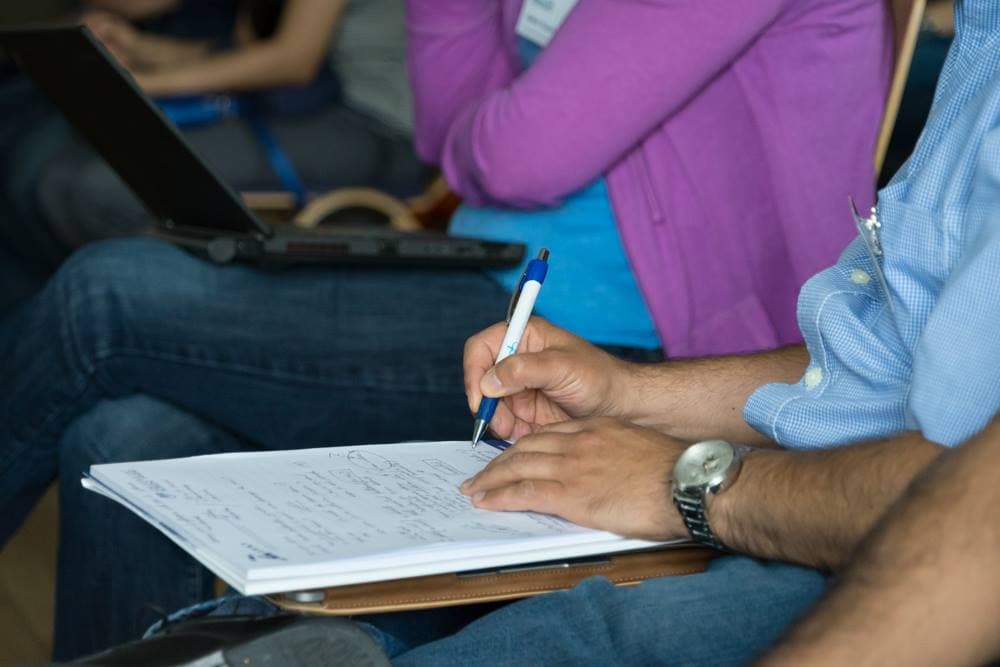 A student writes notes with a pen on a notepad during a lecture, a scene for comparing the types of note-taking (photo: Wechselberger, Wikimedia Commons, CC0)