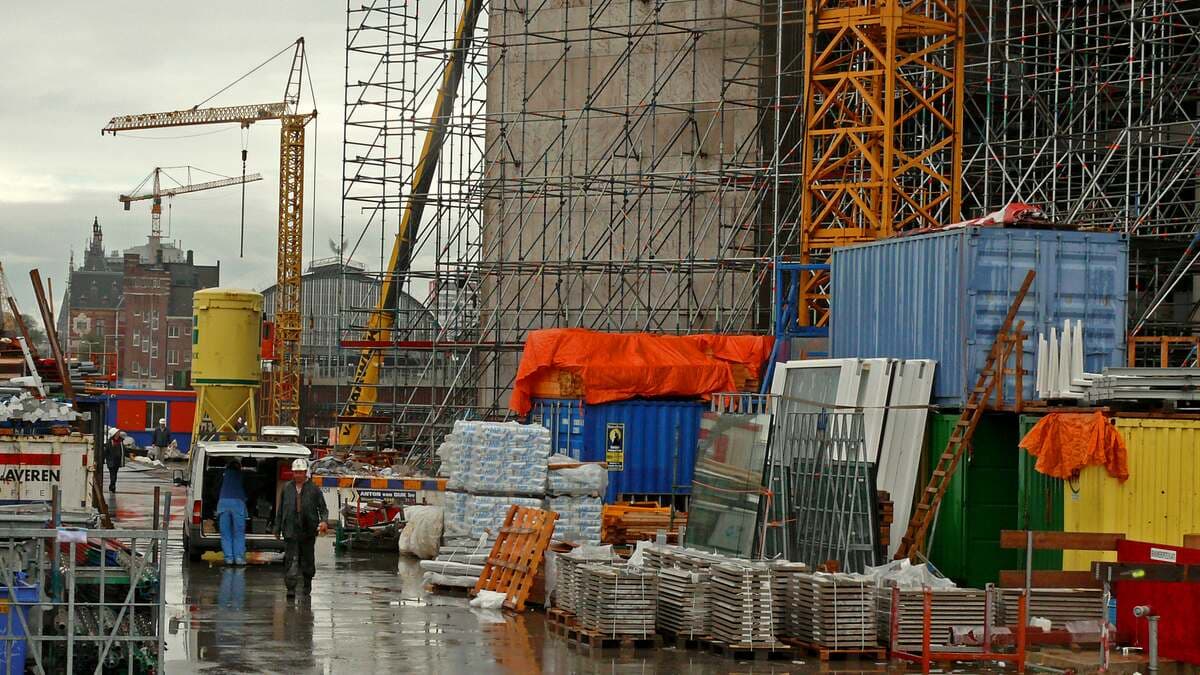 Construction scaffolding around a building site, the visual metaphor for the scaffolding tax in AI prompting: structure you build to support the work, which eventually has to come down