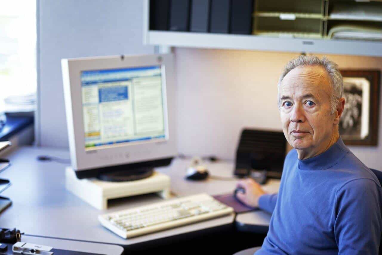 Intel CEO Andy Grove sitting in front of a computer, looking at the camera.