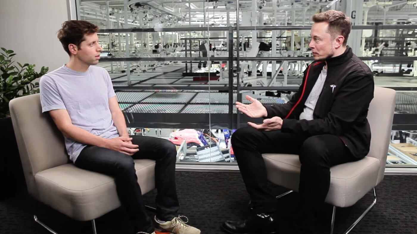 Sam Altman and Elon Musk during a conversation at a Tesla plant.