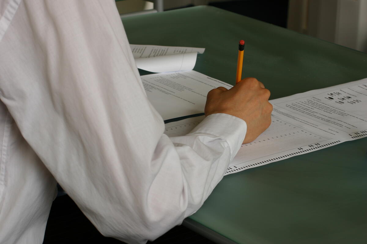 A student writing exam papers in a classroom