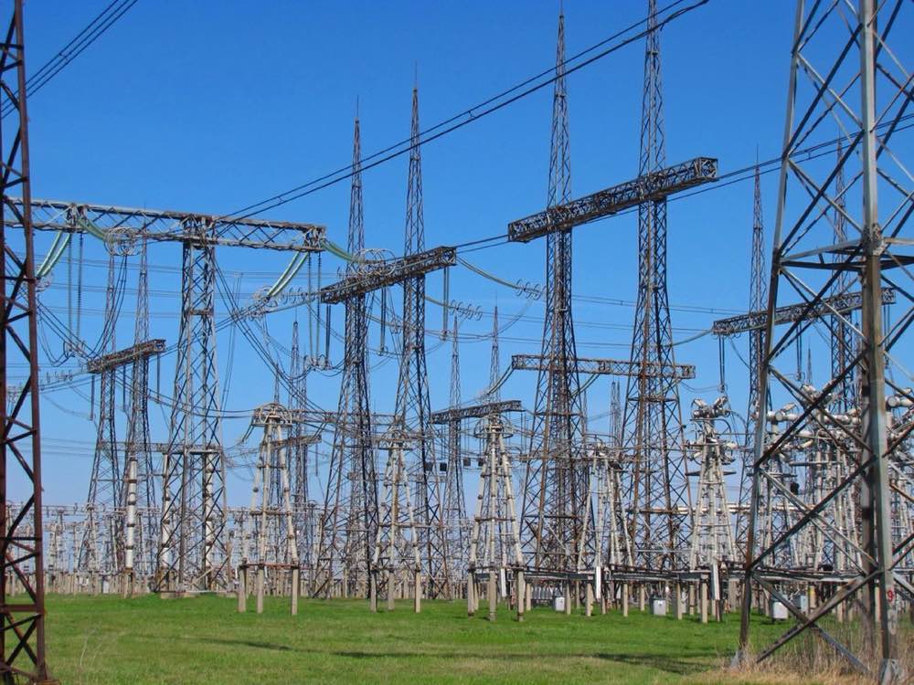 High-voltage switchyard of a 750 kV electrical substation — rows of towers, insulators, and busbars